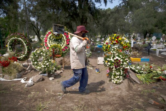 A grave digger walks in the COVID-19 section of the cemetery of San Lorenzo Tezonco Iztapalapa on the outskirts of Mexico City, Tuesday, Sept. 1, 2020. (AP Photo/Marco Ugarte)