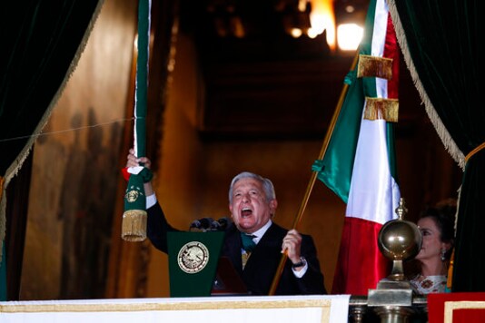 Mexican President Andres Manuel Lopez Obrador rings the bell as he gives the annual independence shout from the balcony of the National Palace to kick off subdued Independence Day celebrations amid the ongoing coronavirus pandemic, at the Zocalo in Mexico City, Tuesday, Sept. 15, 2020. Instead of the throngs of supporters who pack the Zocalo in a typical year, this Independence Day the president faced an empty plaza as he gave the traditional 