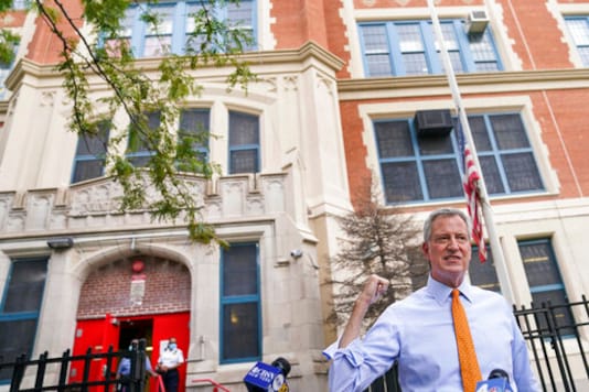 FILE - In this Aug. 19, 2020, file photo, New York Mayor Bill de Blasio speaks to reporters after visiting New Bridges Elementary School to observe pandemic-related safety procedures, in the Brooklyn borough of New York. For most schoolchildren in New York City, Monday, Sept. 21, 2020, will mean back to school, but not back to the classroom. Only pre-kindergarteners and some special education students are scheduled to end a six-month absence from school buildings. (AP Photo/John Minchillo, FIle)