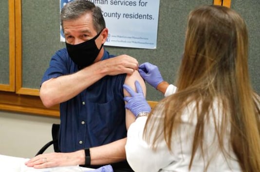 Michelle Winings, R.N., prepares to give Gov. Roy Cooper his flu shot at the Wake County Health Department in Raleigh, N.C., Friday, Sept. 25, 2020. (Ethan Hyman/The News & Observer via AP) Michelle Winings, R.N., prepares to give Gov. Roy Cooper his flu shot at the Wake County Health Department in Raleigh, N.C., Friday, Sept. 25, 2020. (Ethan Hyman/The News & Observer via AP)
