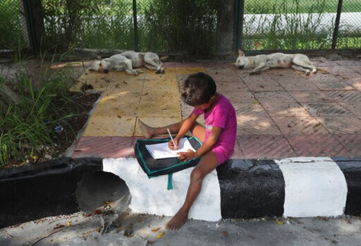 A child practices writing during a sidewalk class taught by an Indian couple, Veena Gupta and her husband Virendra Gupta, in New Delhi, India, on Sept. 3, 2020. It all began when Veena's maid complained that with schools shut, children in her impoverished community were running amok and wasting time. The street-side classes have grown as dozens of children showed keen interest. Now the Guptas, with help from their driver, teach three different groups three times a week, morning and evening. While many private schools switched to digital learning and online classes, children in most government-run schools either dont have that option or dont have the means to purchase digital learning tools like laptops and smartphones. (AP Photo/Manish Swarup)