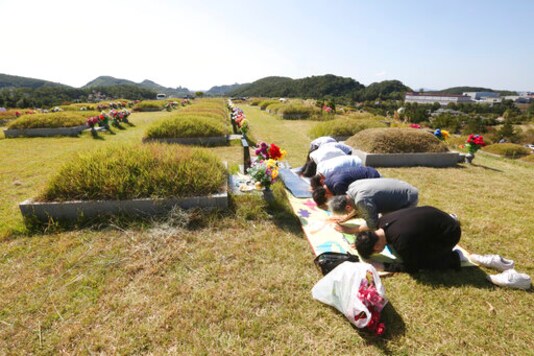 Family members bow to respect at their ancestral cemetery ahead of Chuseok holiday, the Korean version of Thanksgiving Day, at a cemetery in Paju, South Korea, Sunday, Sept. 27, 2020. South Korea's national cemeteries will be closed during the upcoming Chuseok holiday during the five-day holidays from Sept. 30 to Oct. 4 to prevent the spread of the coronavirus. (AP Photo/Ahn Young-joon)