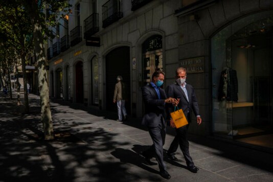 Two men walk in the upmarket neighborhood of Salamanca in Madrid, Spain, Monday, Sept. 28, 2020. The extended region around Madrid, comprising a population of 6.6 million, is struggling to control coronavirus outbreaks. Heightened restrictions in some of Madrid's working-class neighborhoods brought a heated debate over the prevalence of inequality in Spain. (AP Photo/Bernat Armangue)