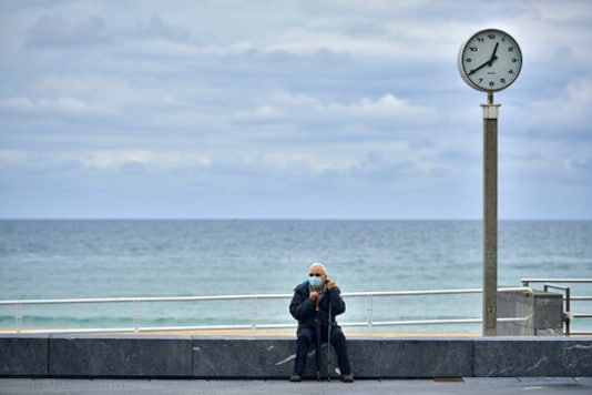 A man wearing face mask protection to prevent the spread of the coronavirus rests along a promenade close to the beach, in San Sebastian, northern Spain, Thursday, Sept. 24, 2020. (AP Photo/Alvaro Barrientos)