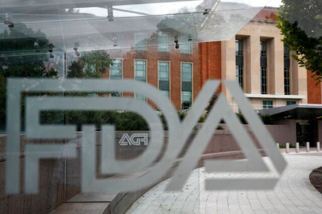 FILE - This Aug. 2, 2018, file photo shows the U.S. Food and Drug Administration building behind FDA logos at a bus stop on the agency's campus in Silver Spring, Md.  In a report to Congress and an accompanying playbook for states and localities, key federal health agencies and the Defense Department sketched out complex plans for a vaccination campaign to begin gradually early next year or later in 2020, eventually ramping up to reach any American who wants a shot. The Pentagon is involved with the distribution of vaccines, but civilian health workers will be the ones giving shots. (AP Photo/Jacquelyn Martin, File)