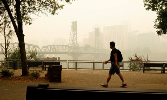 डॉन रेयान द्वारा प्रदान की गई इस तस्वीर में, एक पैदल यात्री विल्मेट ब्रिज और डाउनटाउन पोर्टलैंड, ओरे से गुजरता है, बुधवार को वाइल्डफायर से भारी धुएं में लिपटा हुआ, 16 सितंबर, 2020। (एपी के माध्यम से डॉन रयान)