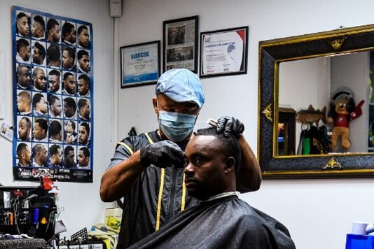James Bennett speaks as he gets a haircut and free counselling by Antonio Wiggins (L) at a barber shop in Jackson, Mississippi. (Photo by CHANDAN KHANNA / AFP)