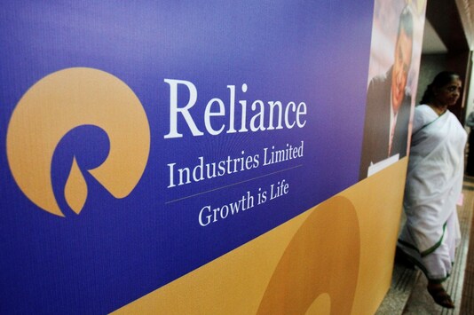 A woman walks past a poster of Reliance Industries installed outside the venue of the company's annual general meeting in Mumbai. (REUTERS/Vivek Prakash/File Photo)