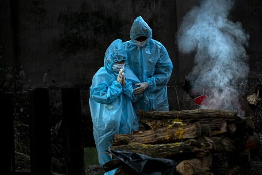 A nine year old boy, left, in personal protective equipment performs rituals during the cremation of his father who died of COVID-19 in Gauhati, India, Monday, Sept. 28, 2020. India’s confirmed coronavirus tally has reached 6 million cases, keeping the country second to the United States in number of reported cases since the pandemic began. (AP Photo/Anupam Nath)