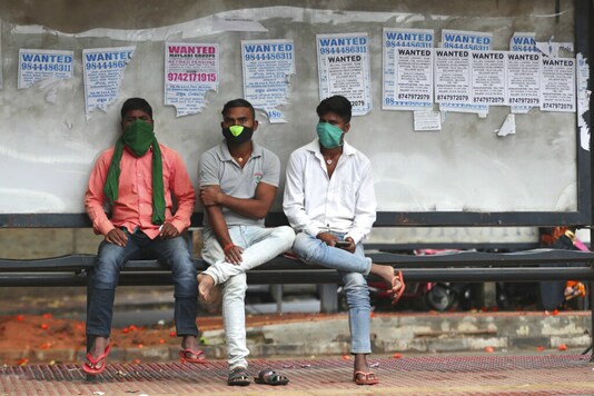 People in masks wait at a bus stop in Bengaluru. (AP)