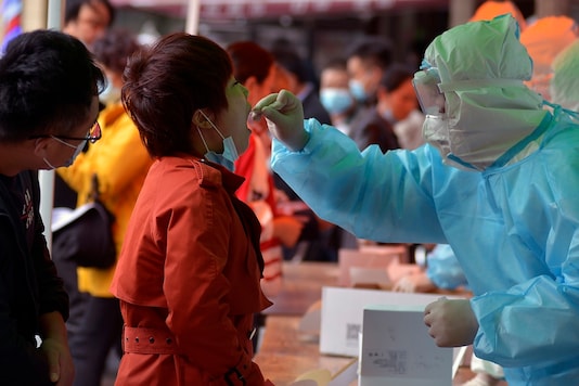 A medical staff takes a swab from a woman as residents line up for the COVID-19 test near the residential area in Qingdao in east China's Shandong province on Monday, Oct. 12, 2020. (Chinatopix ia AP) A medical staff takes a swab from a woman as residents line up for the COVID-19 test near the residential area in Qingdao in east China's Shandong province on Monday, Oct. 12, 2020. (Chinatopix ia AP)