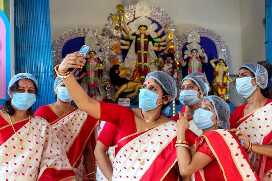South Dinajpur: Women take a selfie in front of the idol of Goddess Durga after West Bengal Chief Minister Mamata Banerjee virtually inaugurated their community Durga Puja, at Balurghat in South Dinajpur district, Wednesday, Oct. 14, 2020. (PTI Photo)( South Dinajpur: Women take a selfie in front of the idol of Goddess Durga after West Bengal Chief Minister Mamata Banerjee virtually inaugurated their community Durga Puja, at Balurghat in South Dinajpur district, Wednesday, Oct. 14, 2020. (PTI Photo)(