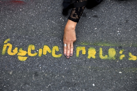 A person flashes the three-fingers salute in the middle of a message painted on the pavement during a Thai anti-government mass protest, on the 47th anniversary of the 1973 student uprising, near the Democracy monument, in Bangkok, Thailand October 14, 2020. REUTERS/Soe Zeya Tun A person flashes the three-fingers salute in the middle of a message painted on the pavement during a Thai anti-government mass protest, on the 47th anniversary of the 1973 student uprising, near the Democracy monument, in Bangkok, Thailand October 14, 2020. REUTERS/Soe Zeya Tun