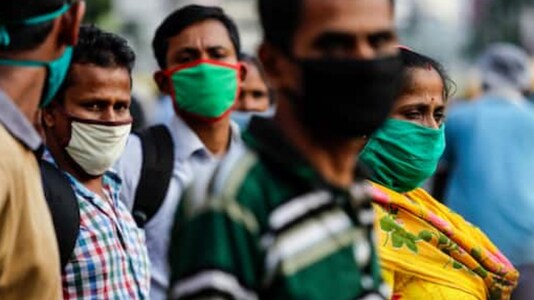 Commuters wearing face masks as a precautionary measure against the coronavirus wait for a bus in Kolkata, on October 10, 2020. (AP Photo/Bikas Das)