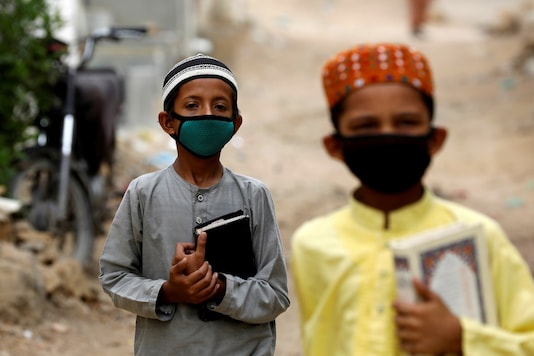 Boys wear protective masks as they head to the madrasa (religious school). Boys wear protective masks as they head to the madrasa (religious school).