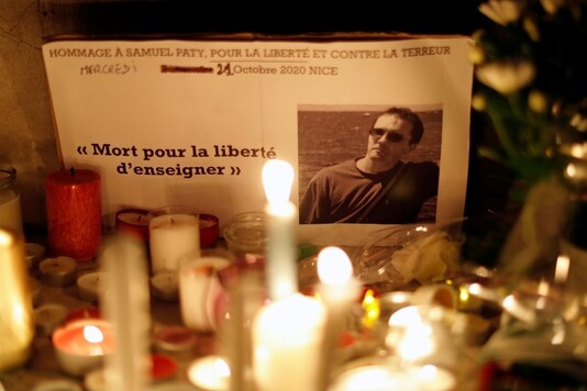 Candles are lit at a makeshift memorial as people gather to pay homage to Samuel Paty, the French teacher who was beheaded on the streets of the Paris suburb of Conflans-Sainte-Honorine, as part of a national tribute, in Nice, France, October 21, 2020. REUTERS/Eric Gaillard
