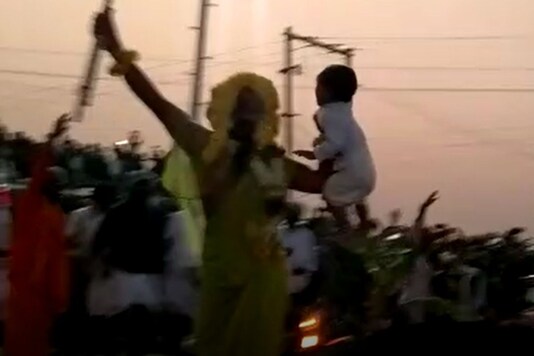Grab from the viral video shows the priest walking on coals with a child.