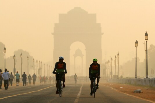 Two men cycle in front of India Gate which is shrouded in smog (Reuters)
