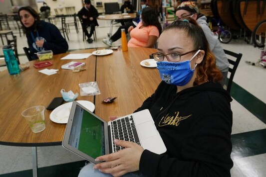 Charisma Poliandro, right, sits with several teachers as she listens during a combination trivia/current events quiz and pizza party in the cafeteria at West Brooklyn Community High School, Thursday, Oct. 29, 2020, in New York. (AP Photo/Kathy Willens)