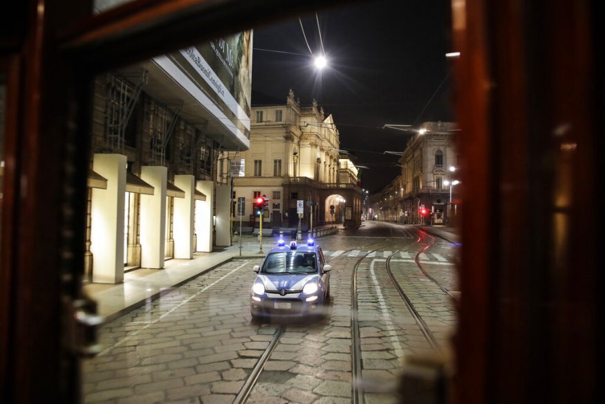  A police car follows a tram streetcar running along an empty street by the La Scala theater, in Milan. (Image: AP)