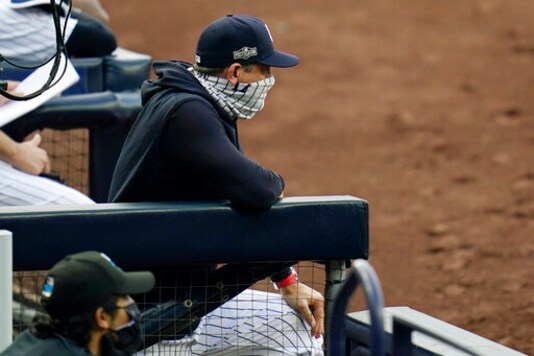 New York Yankees manager Aaron Boone wears a mask as he stands in the dugout during the third inning in Game 4 of a baseball American League Division Series against the Tampa Bay Rays, Thursday, Oct. 8, 2020, in San Diego. (AP Photo/Gregory Bull)