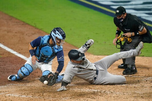 Tampa Bay Rays catcher Mike Zunino drops the ball as he tries to put the tag on New York Yankees' Kyle Higashioka (66) who scored on a single to center field by Aaron Hicks during the ninth inning in Game One of a baseball American League Division Series Monday, Oct. 5, 2020, in San Diego. (AP Photo/Jae C. Hong)