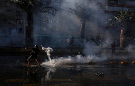 A demonstrator returns a tear gas canister fired by police during a protest against police in reaction to a video that appears to show an officer pushing a youth off a bridge the previous day at a protest, in Santiago, Chile, Saturday, Oct. 3, 2020. (AP Photo/Esteban Felix) A demonstrator returns a tear gas canister fired by police during a protest against police in reaction to a video that appears to show an officer pushing a youth off a bridge the previous day at a protest, in Santiago, Chile, Saturday, Oct. 3, 2020. (AP Photo/Esteban Felix)