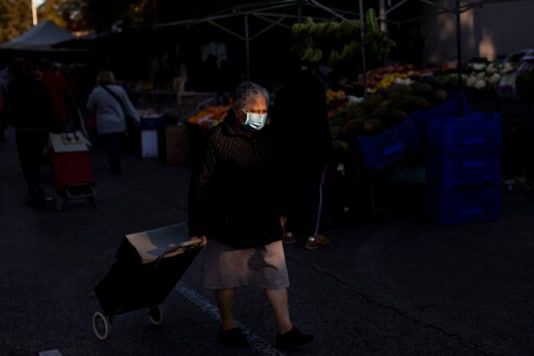 An elderly woman wearing a face mask to prevent the spread of coronavirus walks along street stalls at a fruit market in Madrid, Spain, Tuesday, Oct. 13, 2020. (AP Photo/Bernat Armangue) An elderly woman wearing a face mask to prevent the spread of coronavirus walks along street stalls at a fruit market in Madrid, Spain, Tuesday, Oct. 13, 2020. (AP Photo/Bernat Armangue)
