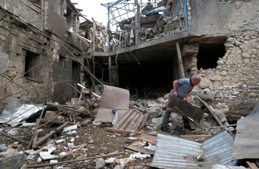 A man throws debris in the yard of a house destroyed by shelling by Azerbaijan's artillery during a military conflict in Stepanakert, the separatist region of Nagorno-Karabakh, Friday, Oct. 9, 2020. The latest outburst of fighting between Azerbaijani and Armenian forces began Sept. 27 and marked the biggest escalation of the decades-old conflict over Nagorno-Karabakh. The region lies in Azerbaijan but has been under control of ethnic Armenian forces backed by Armenia since the end of a separatist war in 1994. (AP Photo) A man throws debris in the yard of a house destroyed by shelling by Azerbaijan's artillery during a military conflict in Stepanakert, the separatist region of Nagorno-Karabakh, Friday, Oct. 9, 2020. The latest outburst of fighting between Azerbaijani and Armenian forces began Sept. 27 and marked the biggest escalation of the decades-old conflict over Nagorno-Karabakh. The region lies in Azerbaijan but has been under control of ethnic Armenian forces backed by Armenia since the end of a separatist war in 1994. (AP Photo)