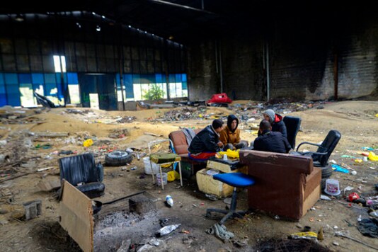 FILE - In this Saturday, Sept. 26, 2020 file photo, migrants sit in an abandoned factory outside Velika Kladusa, Bosnia. Bosnian authorities have started emptying U.N.-run migrant camps in town centers housing hundreds of people, moving residents to a crowded, out-of-the-way facility thats not equipped for winter conditions  or just leaving them to fend for themselves in the woods. (AP Photo/Kemal Softic, File)