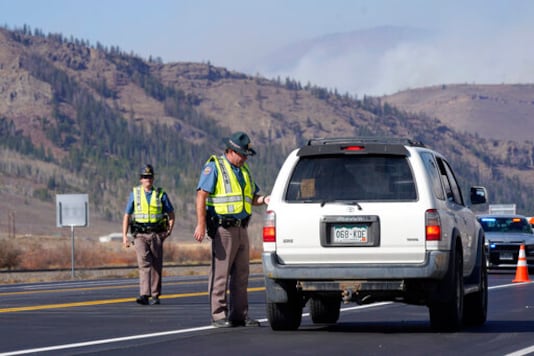 As smoke rises from mountain ridges, Colorado State Partrol troopers stop motorists at a roadblock on Highway 34 as a wildfire burns Thursday, Oct. 22, 2020, near Granby, Colo. (AP Photo/David Zalubowski) As smoke rises from mountain ridges, Colorado State Partrol troopers stop motorists at a roadblock on Highway 34 as a wildfire burns Thursday, Oct. 22, 2020, near Granby, Colo. (AP Photo/David Zalubowski)
