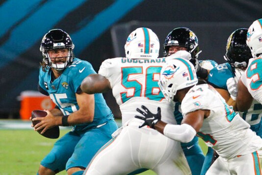 Miami Dolphins defensive tackle Davon Godchaux (56) pressures Jacksonville Jaguars quarterback Gardner Minshew, left, as he looks for a receiver during the first half of an NFL football game, Thursday, Sept. 24, 2020, in Jacksonville, Fla. (AP Photo/Stephen B. Morton)