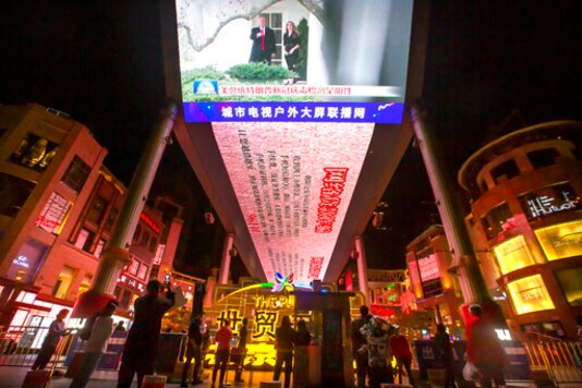 FILE - In this Oct. 2, 2020, file photo, people watch a large screen showing President Donald Trump and First Lady Melania Trump during a news report from Chinese state television about Trump testing positive for the coronavirus in Beijing. Chinese leaders hope Washington will tone down conflicts over trade, technology and security if Joe Biden wins the Nov. 3 presidential election. But any shift is likely to be in style, not substance, as frustration with Beijing increases across the American political spectrum. (AP Photo/Mark Schiefelbein, File)