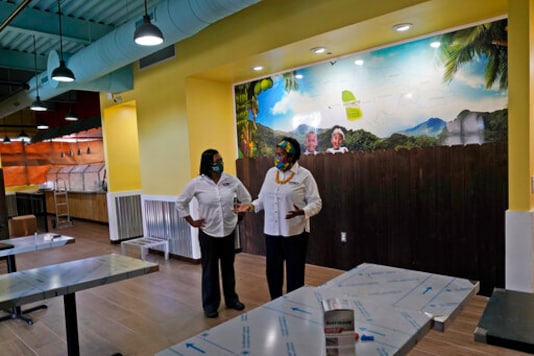 In this Aug. 26, 2020, photo Sophia Bramwell, left, and Antoinette Henry, right, talk at the soon to be opened Dutch Pot Jamaican Restaurant in Miami Gardens, Fla. Voters in the Democratic stronghold of Broward County are eager to defeat Trump, but say they are even more energized to turn out in support of California Sen. Kamala Harris, Bidens running mate whose father is Jamaican. The fact she has a lineage means you are going to see a lot of Jamaicans voting even if they were not doing so before, said Henry, Part of Jamaica will be in the White House. (AP Photo/Lynne Sladky) In this Aug. 26, 2020, photo Sophia Bramwell, left, and Antoinette Henry, right, talk at the soon to be opened Dutch Pot Jamaican Restaurant in Miami Gardens, Fla. Voters in the Democratic stronghold of Broward County are eager to defeat Trump, but say they are even more energized to turn out in support of California Sen. Kamala Harris, Bidens running mate whose father is Jamaican. The fact she has a lineage means you are going to see a lot of Jamaicans voting even if they were not doing so before, said Henry, Part of Jamaica will be in the White House. (AP Photo/Lynne Sladky)