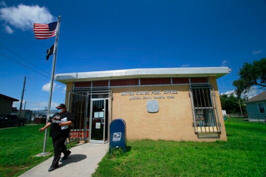 The post office in Mission, S.D. saw a steady flow of people on Aug. 6, 2020. The post office is one of four on the roughly 2,000 square miles (5,180 square kilometers) of the Rosebud Indian Reservation (AP Photo/Stephen Groves)