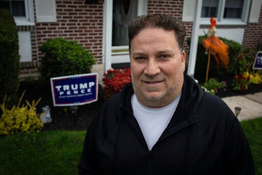 Scott Brady stands in front of his house with a Trump campaign sign in Springfield, Pa. on Wednesday, Oct. 28, 2020. Once a Democrat, Brady says he switched parties to vote for Donald Trump in 2016, and plans to vote for him again in 2020. (AP Photo/Robert Bumsted)