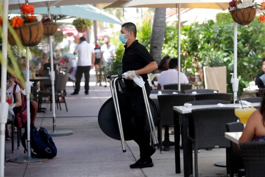 In this July 12, 2020, file photo, a waiter wears a protective face mask and gloves while working at the il bolognese restaurant along Ocean Drive during the coronavirus pandemic, in Miami Beach, Fla. (AP Photo/Lynne Sladky, File)