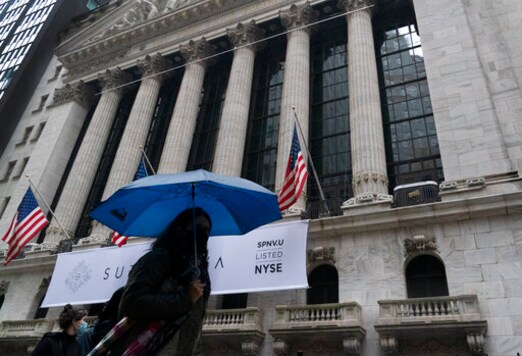 A woman with an umbrella passes the New York Stock Exchange, Monday, Oct. 26, 2020. U.S. stocks are drifting Tuesday, Oct. 27, 2020, as momentum slows a day after Wall Street slumped to its worst loss in a month on worries about rising virus counts and Washingtons inability to deliver more aid to the economy.  The (AP Photo/Mark Lennihan)