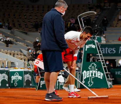 Serbia's Novak Djokovic jokes as he briefly helps clean the court of rain water in the third round match of the French Open tennis tournament against Colombia's Daniel Elahi Galan at the Roland Garros stadium in Paris, France, Saturday, Oct. 3, 2020. (AP Photo/Christophe Ena) Serbia's Novak Djokovic jokes as he briefly helps clean the court of rain water in the third round match of the French Open tennis tournament against Colombia's Daniel Elahi Galan at the Roland Garros stadium in Paris, France, Saturday, Oct. 3, 2020. (AP Photo/Christophe Ena)