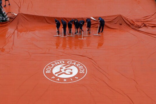 Stadium workers remove rain water from the cover of Suzanne Lenglen court as rain delayed fourth round matches of the French Open tennis tournament at the Roland Garros stadium in Paris, France, Monday, Oct. 5, 2020. (AP Photo/Alessandra Tarantino)