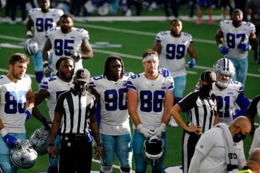 Dallas Cowboys players, Blake Bell (80), DeMarcus Lawrence (90), Dalton Schultz (86), Ezekiel Elliott (21) and others look on as quarterback Dak Prescott, not shown, receives medical attention after suffering a lower right leg injury running the ball against the New York Giants in the second half of an NFL football game in Arlington, Texas, Sunday, Oct. 11, 2020. (AP Photo/Michael Ainsworth)