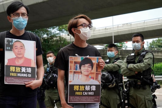 Pro-democracy activists holding picture of detained Chinese human rights activists, protest outside the Chinese liaison office in Hong Kong, Thursday, Oct. 1, 2020 on the occasion of China's National Day. They demanded to release the 12 Hong Kong activists detained at sea by Chinese authorities. (AP Photo/Kin Cheung)
