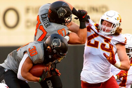 File-This Oct. 24, 2020, file photo shows Oklahoma State lineman Logan Carter (87) grabbing the jersey of Iowa State linebacker Mike Rose (23) while Oklahoma State running back Chuba Hubbard (30) attempts to sneak by during an NCAA college football game in Stillwater, Okla. Rose, like everybody else in college football, had no idea last spring if there would be a season. Iowa State's junior linebacker wanted to be ready just in case, so day in and day out for three months he went to his high school in the Cleveland suburb of Brecksville, Ohio, to do workouts prescribed by the Cyclones' new strength staff. (AP Photo/Brody Schmidt, File)