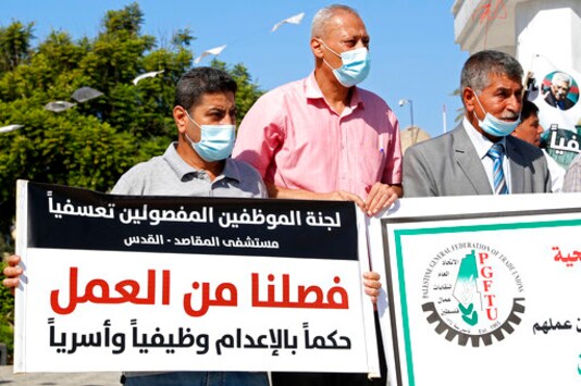 Medical workers wear face masks and hold placards while staging a sit-in protest at the Unknown Soldier Square in Gaza City, Wednesday, Oct. 21, 2020. Arabic reads: Medical workers wear face masks and hold placards while staging a sit-in protest at the Unknown Soldier Square in Gaza City, Wednesday, Oct. 21, 2020. Arabic reads:
