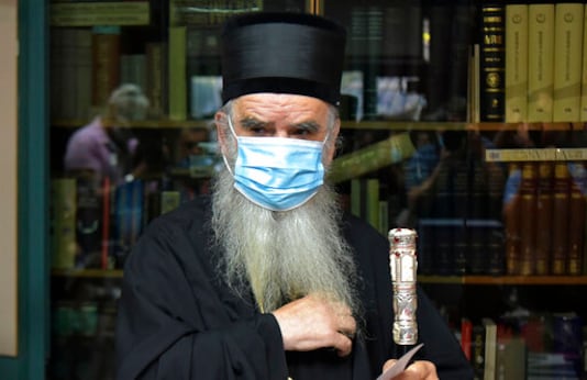 In this photo taken Sunday, Aug. 30, 2020, Serbian Orthodox bishop Amfilohije wearing a mask against the spread of the new coronavirus prepares to vote in parliamentary elections at a polling station in Cetinje, some 30 km south of Podgorica, Montenegro. The head of the Serbian Orthodox Church in Montenegro, which led months of protests against the small Balkan state's pro-Western government, has been hospitalized after testing positive for the coronavirus. (AP Photo/Risto Bozovic) In this photo taken Sunday, Aug. 30, 2020, Serbian Orthodox bishop Amfilohije wearing a mask against the spread of the new coronavirus prepares to vote in parliamentary elections at a polling station in Cetinje, some 30 km south of Podgorica, Montenegro. The head of the Serbian Orthodox Church in Montenegro, which led months of protests against the small Balkan state's pro-Western government, has been hospitalized after testing positive for the coronavirus. (AP Photo/Risto Bozovic)