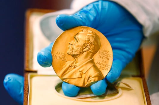 FILE - In this April 17, 2015, file photo, a national library employee shows a gold Nobel Prize medal in Bogota, Colombia. The Nobels, with new winners announced starting Monday, Oct. 5, 2020, often concentrate on unheralded, methodical, basic science. (AP Photo/Fernando Vergara, File) FILE - In this April 17, 2015, file photo, a national library employee shows a gold Nobel Prize medal in Bogota, Colombia. The Nobels, with new winners announced starting Monday, Oct. 5, 2020, often concentrate on unheralded, methodical, basic science. (AP Photo/Fernando Vergara, File)