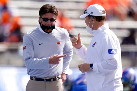 Oklahoma State head coach Mike Gundy, left, and Kansas head coach Les Miles talk before an NCAA college football game in Lawrence, Kan., Saturday, Oct. 3, 2020. (AP Photo/Orlin Wagner)