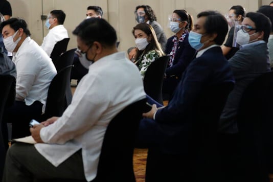 Filipino lawmakers wear face masks as they attend a session before swearing in Rep. Lord Allan Velasco as new house speaker at the Celebrity sports club in Quezon city, Philippines, Monday, Oct. 12, 2020. A large faction of Philippine legislators in the House of Representatives has elected a new leader but the incumbent speaker declared the vote a travesty in a tense political standoff between two allies of the president. (AP Photo/Aaron Favila) Filipino lawmakers wear face masks as they attend a session before swearing in Rep. Lord Allan Velasco as new house speaker at the Celebrity sports club in Quezon city, Philippines, Monday, Oct. 12, 2020. A large faction of Philippine legislators in the House of Representatives has elected a new leader but the incumbent speaker declared the vote a travesty in a tense political standoff between two allies of the president. (AP Photo/Aaron Favila)