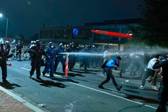 Washington Metropolitan Police Department police officers shoot pepper spray at demonstrators outside of the fourth district police station in Washington, Wednesday, Oct. 28, 2020. Demonstrators gathered at the police station in protest over a fatal a crash involving a moped driver who died when he police were attempting to pull him over. The crash happened last Friday. (AP Photo/Jose Luis Magana)