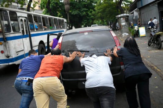FILE - In this May 25, 2020 file photo, people push a car that ran out of gas to a state-run oil company PDVSA filling station during a fuel crunch in Caracas, Venezuela. With motorists waiting in lines to fill up their cars with gas that is increasingly scarce, the government proposed in Oct. 2020 to the Constitutional Assembly an Anti-Blockade Law, to get around U.S. sanctions. (AP Photo/Matias Delacroix, File) FILE - In this May 25, 2020 file photo, people push a car that ran out of gas to a state-run oil company PDVSA filling station during a fuel crunch in Caracas, Venezuela. With motorists waiting in lines to fill up their cars with gas that is increasingly scarce, the government proposed in Oct. 2020 to the Constitutional Assembly an Anti-Blockade Law, to get around U.S. sanctions. (AP Photo/Matias Delacroix, File)